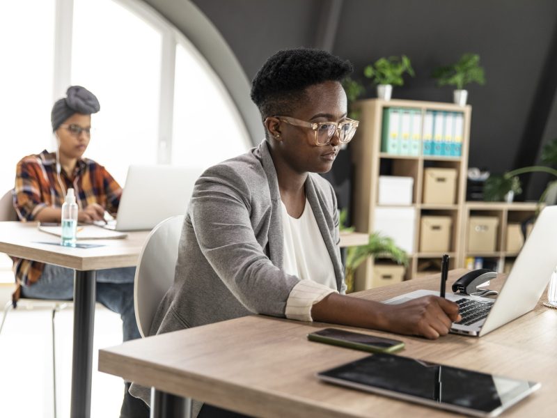 Two diligent female entrepreneurs working at their desk at the office, using laptops. via Getty Images