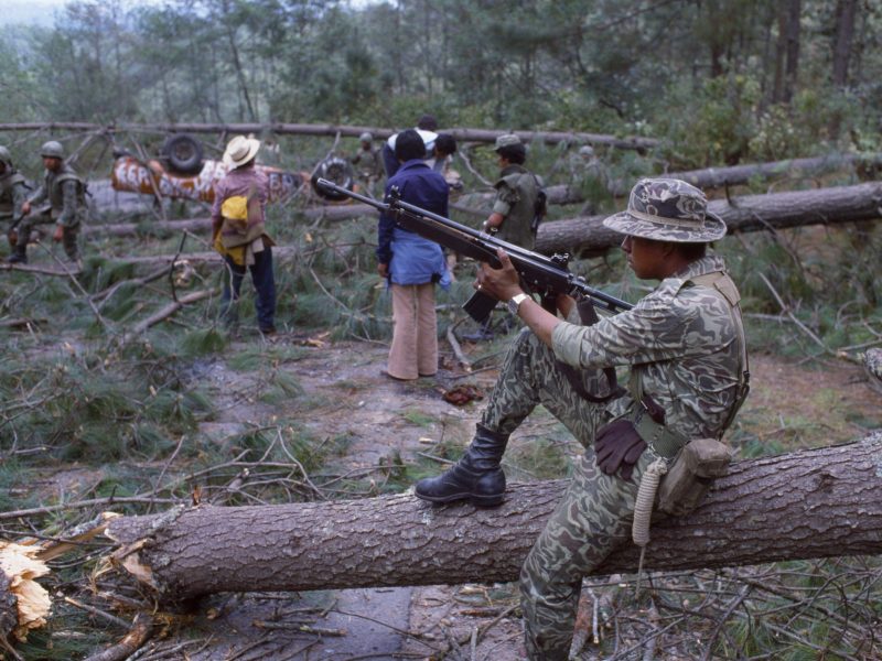 View of a Guatemalan Army soldier as he sits on a felled tree on a section of the Pan American Highway, Los Encuentros, Guatemala, March 7, 1982. Photo by Robert Nickelsberg/Getty Images