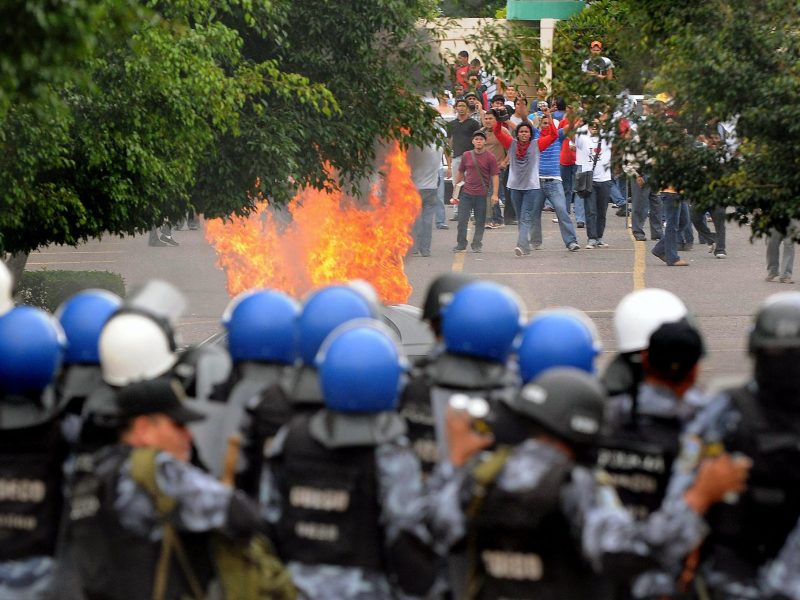 Honduran riot policemen form a barrier during clshes with students from the Universidad Nacional Autonoma de Honduras (UNAH), who demand the restitution of ousted President Manuel Zelaya, on August 5, 2009 in Tegucigalpa. Photo by ORLANDO SIERRA/AFP via Getty Images